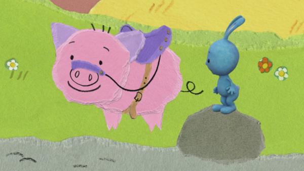 Kikaninchen steht auf einem Stein vor einem rosa Schwein mit einem Sattel