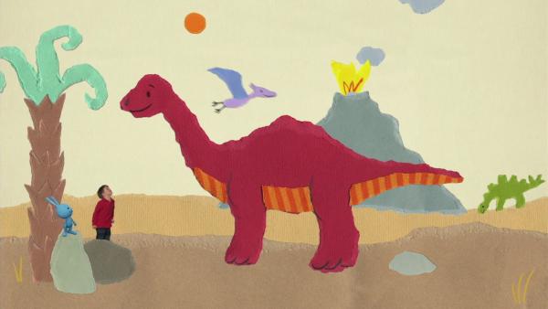 Kikaninchen und ein Kind vor einem großen roten Dino