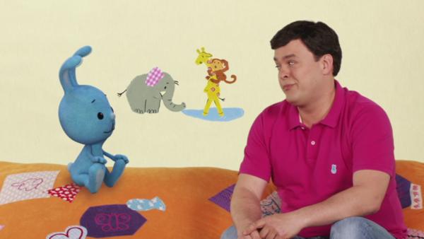 Kikaninchen und Christian unterhalten sich, im Hintergrund sind Tiere zu sehen.