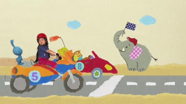 Kikaninchen und ein Kind fahren auf einem Motorrad über die Ziellinie.