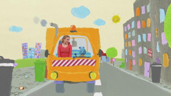 Kikaninchen und Anni fahren mit einem orangenen Müllwagen durch die Stadt.