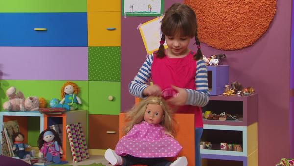 Henriette schneidet ihrer Puppe eine schicke neue Frisur.