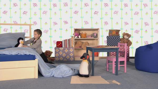 Ein Mädchen und zwei Pinguine in einem Kinderzimmer.