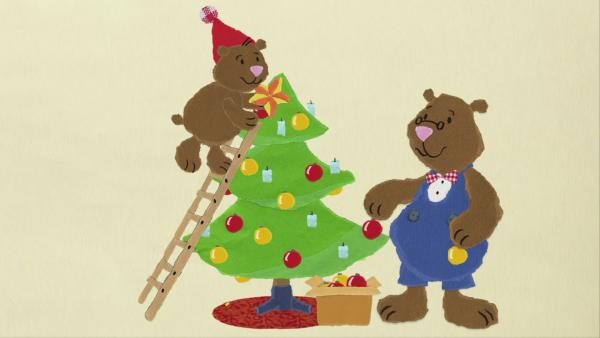 Zwei Bären schmücken den Weihnachtsbaum.