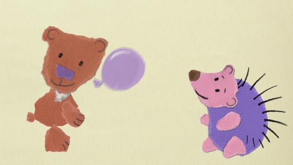 Ein Teddybär und ein Igel spielen mit einem lilanen Luftballon.