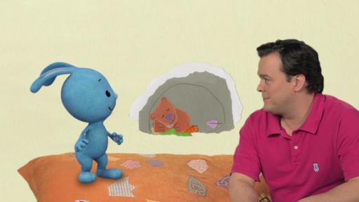 Christian und Kikaninchen sizen auf einer Decke, in einer Höhle ein schlafende Bär