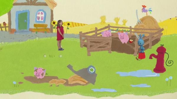 KiKANiNCHEN und ein kleines Mädchen stehen bei den Schweinen auf dem Bauernhof.