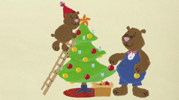 Zwei Bären schmücken einen Weihnachtsbaum.