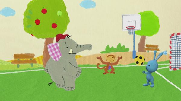 Affe, Elefant und Kikaninchen auf einem Fußballplatz.