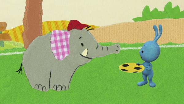 Kikaninchen gibt dem Elefanten eine Frisbeescheibe.