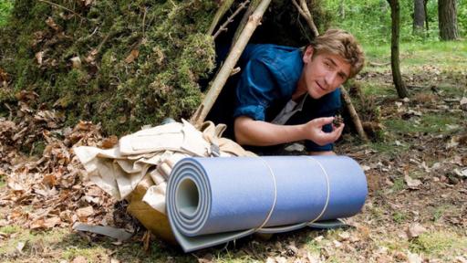 Fritz liegt unter einem selbstgebauten Wetterschutz im Wald