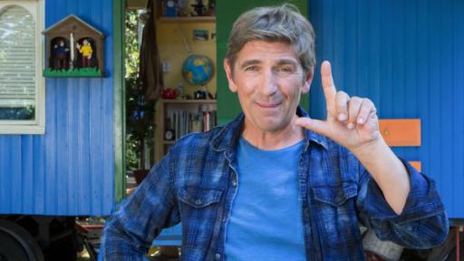 Rechts Links Teaser 01 | Rechte: ZDF Fritz steht vor dem Bauwagen und zeigt mit den Fingern der linken Hand ein L