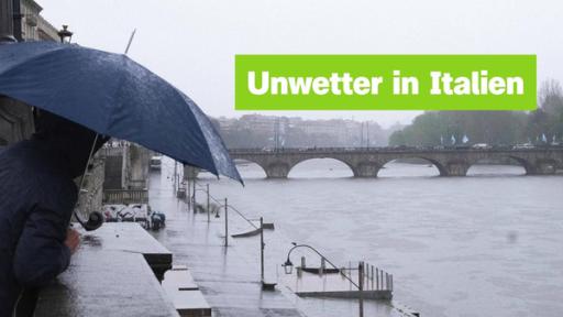 Sendung 18. April | Rechte: IMAGO / ZUMA Press Eine Person steht mit Regenschirm an einer verregneten Flusspromenade. Darüber der Schriftzug: "Unwetter in Italien".