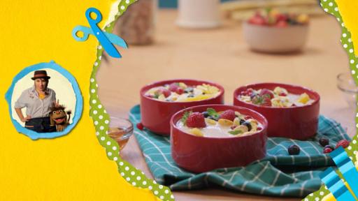 Drei rote Schüsseln mit selbstgemachten Smülis. Einer Mischung aus Müsli und Smoothie garniert mit Erdbeeren und Himbeeren stehen auf einem Tisch. Daneben sind Moppi und Nina zu sehen.