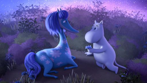 Mumintroll (rechts) und ein blaues Seepferdchen mit rosafarbenem Blumenmuster (links) liegen auf einer Wiese. Mumintroll überreicht dem Seepferdchen eine kleine blaue Blume.