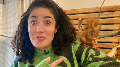 Eichhörnchen in Not - Vera rettet die kleinen Nager | Rechte: WDR | tvision Reporterin Tessniem mit einem Eichhörnchen auf der Schulter, das eine halbe Marone futtert. Tessniem zeigt auf das Eichhörnchen und guckt begeistert.