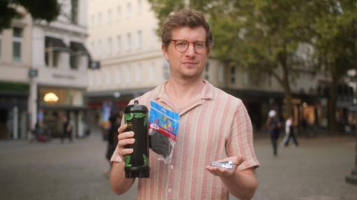 Lachgas - Haha, witzig? | Rechte: WDR | tvision Reporter Robert Meyer hält kleine Sahnekartuschen, schwarze Luftballons und eine große Lachgas-Kartusche in der Hand.