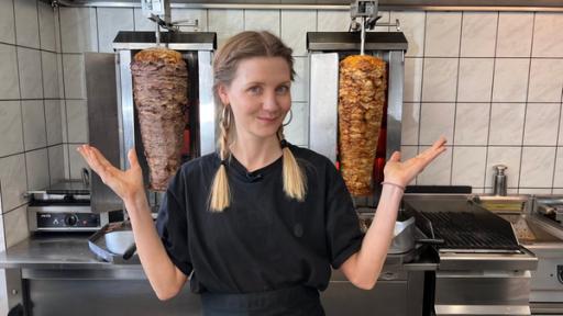 Luxus Döner? – Warum die Preise so steigen | Rechte: WDR/tvision Reporterin Jana steht fragend in einem Dönerladen. Hinter ihr stehen zwei Dönerspieße.