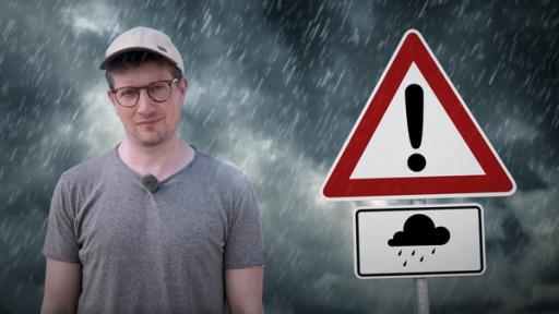 neuneinhalb kompakt - Hochwasserschutz | Rechte: WDR | tvision Reporter Robert steht vor einem Hintergrund mit dunkler Wolkenfront, aus der es regnet. Neben ihm ist ein Schild zu sehen, das vor Hochwasser warnt.