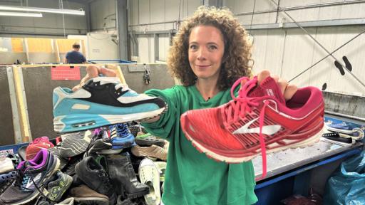 Reporterin Gesa steht in einem Textilsortierunternehmen und hält zwei Paar Sneaker in die Kamera.