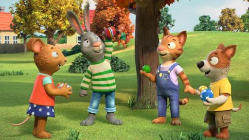 Das Superball-Spiel! | Rechte: © Magic Light Pictures LTD 2023 Draußen im Park auf der Wiese unter einem Baum spielen die Kinder Ball. Posy, die Maus, Pip das Kaninchen, Frankie die Katze und Zac der Hund haben sichtlich Spaß beim gemeinsamen Ballspielen. Alle haben bunte Bälle in den Händen, Zac sogar zwei. Im Hintergrund auf dem Weg vor Häusern kommt Jamila, das Eichhörnchen fröhlich pfeifend angehüpft.