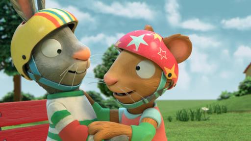 Losgerollt! | Rechte: ZDF Pip (links) und Posy (rechts) umarmen sich und haben einen Fahrradhelm auf. Pips Helm ist gelb und ist bunt gestreift, Posys Helm ist rot und hat gelbe und weisse Sterne.