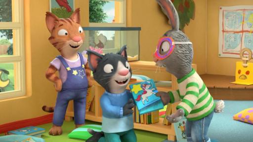 Pip, der Superheld | Rechte: © Magic Light Pictures LTD 2023 Im Wohnzimmer überreicht das Kaninchen Pip, mit Superheldenmaske im Gesicht, seinem Freund, dem Kater Mo, der vor ihm auf dem Teppich kniet, ein Buch. Auf dem Buch-Cover ist ein Einhorn und ein großer Stern. Mo freut sich sehr darüber. Die Katze Frankie steht hinter Mo und blickt lächelnd zu ihren Freunden.