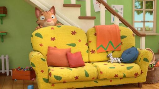Wo ist Frankie? | Rechte: © Magic Light Pictures LTD 2023 Im Wohnzimmer hinter dem bunten Sofa versteckt sich Frankie, die Katze. Vorsichtig schaut sie hinter der hohen Lehne des Sofas hervor. Im Hintergrund hängen bunte, selbst gemalte Bilder am Treppenaufgang und durch ein Fenster blickt man hinaus in den Garten.