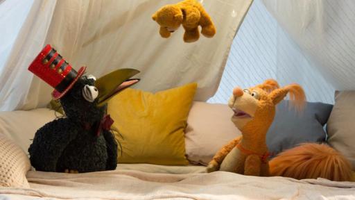 Trolltag | Rechte: ZDF Rudi und Ella hocken in der Kuschelecke und schauen staunend nach oben: Über ihnen hängt Teddy an einem Faden. Rudi trägt einen Zylinder wie ein Zirkusdirektor.