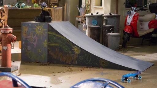Rudis olles Skateboard | Rechte: ZDF Rudi hockt mit seinem Skateboard und einem Helm auf dem Kopf oben auf einer Rampe und schaut sehnsüchtig auf ein schickes, blaues Board, das unten am Boden liegt.