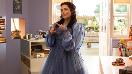 Über Nacht Prinzessin | Rechte: ZDF Siebenstein (Anna Werner Friedmann) als Prinzessin, mit langem, schwarzen Haar und einem blauen Prinzessinnenkleid, steht im Laden und lächelt verschmitzt. Im Hintergrund sieht man die geöffnete Tür zum Hof hin und Regale mit allerlei Krims-Krams.