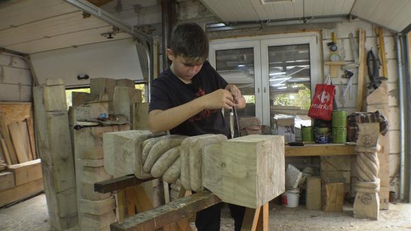 Bogdan zeichnet mit dem Zirkel die Motive auf das Holz.