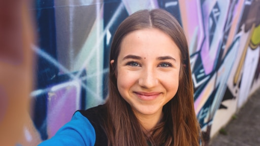 Abschiedvideo Julie Marienfeld | Rechte: MDR / Saxonia Media / KiKA Julie (Rolle Nesrin Schulze) macht ein Foto von sich vor einer bunten Wand.