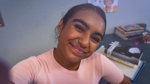Abschiedvideo Sophia Leonie Mauritz Sophia (spielt Reena Kumari) lächelt in die Kamera, hinter ihr ein Schreibtisch.