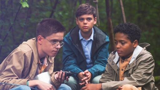 3 Jungs sitzen im Wald.