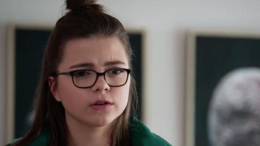 Ein Mädchen mit Brille und grünem Pullover.
