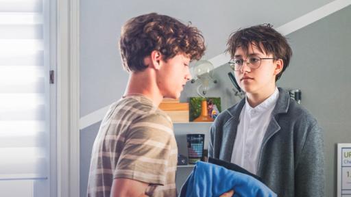 Zwei Jungen stehen sich in einem Zimmer gegenüber.