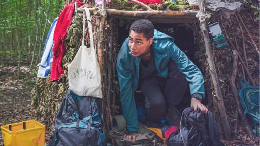 Junge an selbstgebauter Unterkunft im Wald