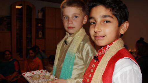 zwei Kinder in Tracht halten ein Tablett mit Gebäck