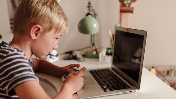 Ein Kind sitzt vor einem Laptop.