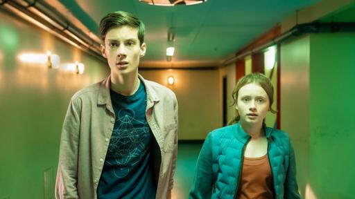 Silverpoint, Staffel 2, Folge 08: Mehr als ein Alien | Rechte: © Zodiak Kids & Family Productions UK Ltd In einem grünlich beleuchteten Flur stehen Bea, gespielt von Aoife Hughes, und Louis, gespielt von Oliver Cunliffe, nebeneinander. Beide schauen ängstlich und angespannt nach vorne.