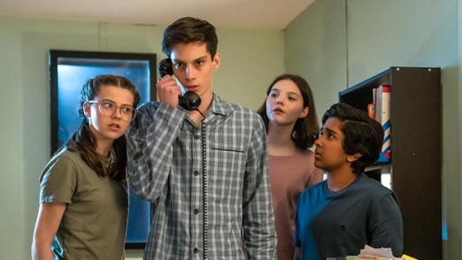 Silverpoint, Staffel 2, Folge 07: Nachtschicht im Schlaflabor | Rechte: © Zodiak Kids & Family Productions UK Ltd In einem Büroraum bei Nacht stehen Monika, gespielt von Lucy Chambers, Isabel, gespielt von Alis Waters, und Glen, dargestellt von Krish Misra, um Louis, Darsteller Oliver Cunliffe, herum. Loius hält einen alten schwarzen Telefonhörer in der Hand. Die drei schauen neugierig und aufmerksam zu Louis, während dieser ernst nach vorne schaut. Alle tragen Schlafanzüge.