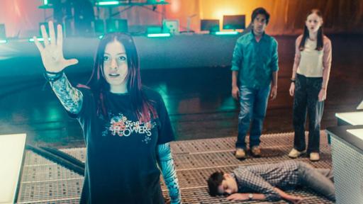 Silverpoint, Staffel 2, Folge 10: Die zweite Chance | Rechte: © Zodiak Kids & Family Productions UK Ltd In der großen Halle auf dem Boden bei den Artefakten liegt Louis mit geschlossenen Augen. Bei ihm stehen Glen und Meg und beobachten Kaz. Kaz hat den Arm gehoben und aus ihrer gespreizter Hand kommt ein weißer dicker Lichtstrahl. Kaz schaut konzentriert in Richtung des Lichtstrahls.