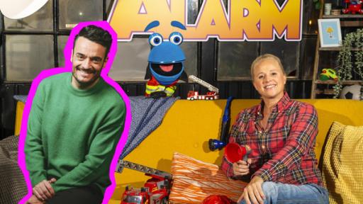 FeuerwehrAlarm mit Giovanni Zarella | Rechte: ZDF Singa sitzt lächelnd auf einem Sofa mit Giovanni Zarella, das SingDing schaut hinter dem Sofa hervor.