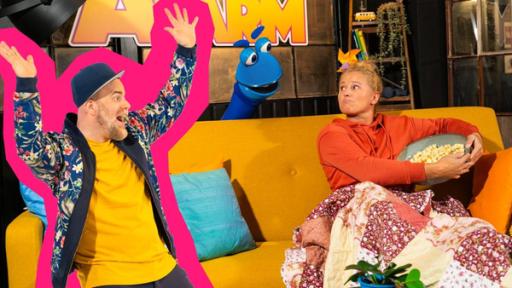 Immer muss ich alles teilen | Rechte: ZDF Singa sitzt mit einer Decke um die Beine gewickelt auf dem Sofa und hält eine große Schüssel mit Popcorn schützend in ihren Armen. Sie schaut skeptisch zum SingDing, dass hinter dem Sofa hervorschaut und gierig in Richtung Popcorn blickt. Links vor dem Sofa steht mit in der Luft ausgebreiteten Armen Sebó, der Singa und das SingDing anlacht.