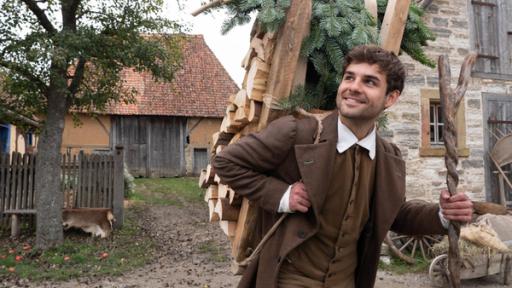 Hans (Lucas Reiber) trägt Holz.