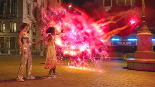 Stromausfall in Paris | Rechte: © 2024 Cottonwood Media - ZDF - ZDF Studios - Opéra National de Paris Abends auf einer Straße in Paris: Jade und Cece werden von dunkler Mystic-Magie angegriffen. Cece wehrt diese mit Wizen-Kräften ab. Ein rot glühender Schutzwall baut sich vor ihnen auf. Jade steht hinter Cece und hält deren Hand fest.