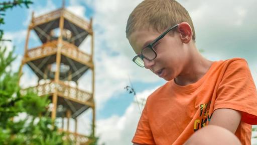 Matus - Teaser - Ich kämpfe gegen Höhenangst | Rechte: ZDF Auf dem Bild ist ein Junge mit orangenem Shirt und Brille der nach unten Schaut. In der Ferne sieht man einen Turm.