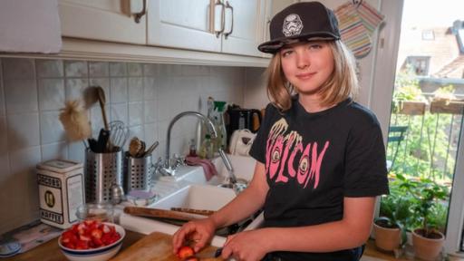 Jakub - Es gibt keinen Planeten B | Rechte: ZDF Jakub hat schulterlanges, blondes Haar und eine schwarze Kappe auf. Er steht in der Küche an einem großen Holzschneidebrett und schneidet Erdbeeren. Neben ihm steht eine große Schüssel mit bereits geschnittenen Erdbeeren. Er schaut in die Kamera und lächelt.