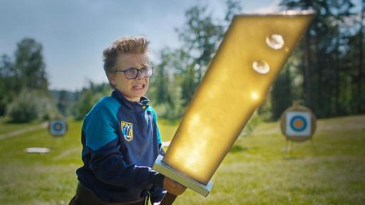 Das geheimnisvolle Super-Schwert | Rechte: © SEEFOOD TV AS 2023/Eirik Evjen Uno steht mit ängstlichem Blick auf einer Wiese, die von Bäumen und Sträuchern umringt ist. Er hält angestrengt ein riesiges golden leuchtendes Schwert mit beiden Händen fest. Im Hintergrund stehen Zielscheiben.